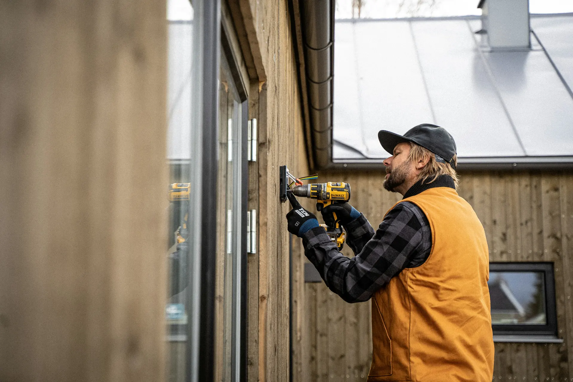 A carpenter using a cordless drill on a timber-clad wall