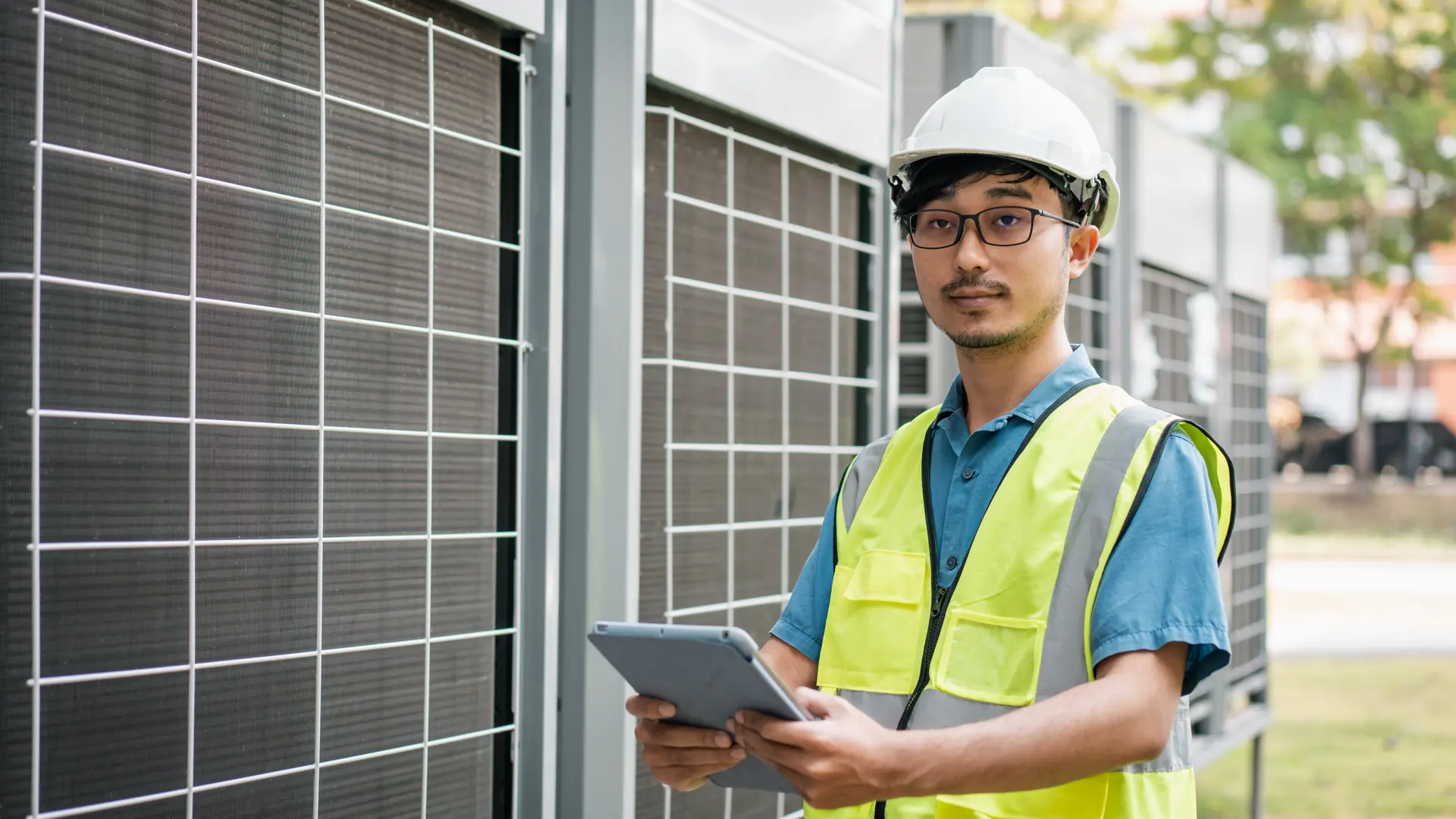 An engineer with a tablet checking an air conditioning unit